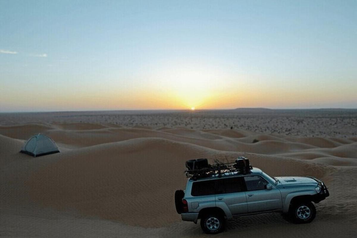 a truck in the desert with the sunset in the background