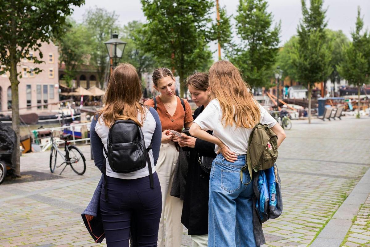 grupp naisi seisab kõnniteel ja vaatab mobiiltelefoni