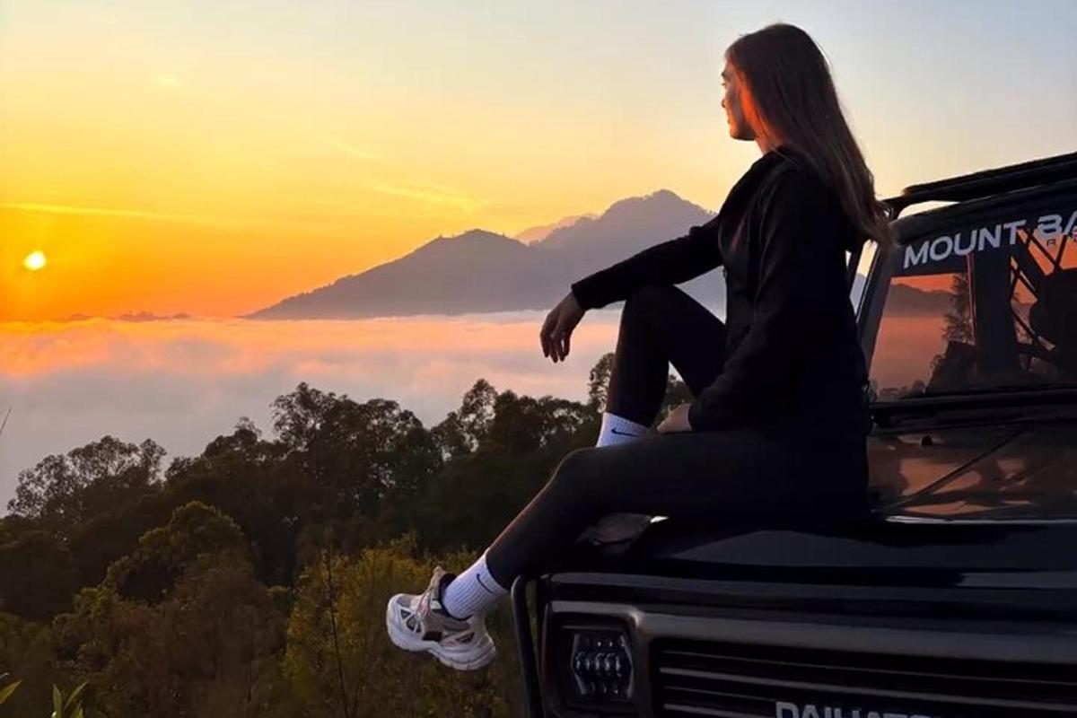 uma mulher sentada na frente de um caminhão olhando o pôr do sol