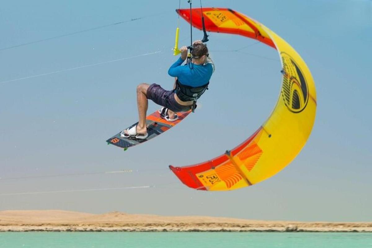 una persona che cavalca una tavola da windsurf e si tiene a un paracadute