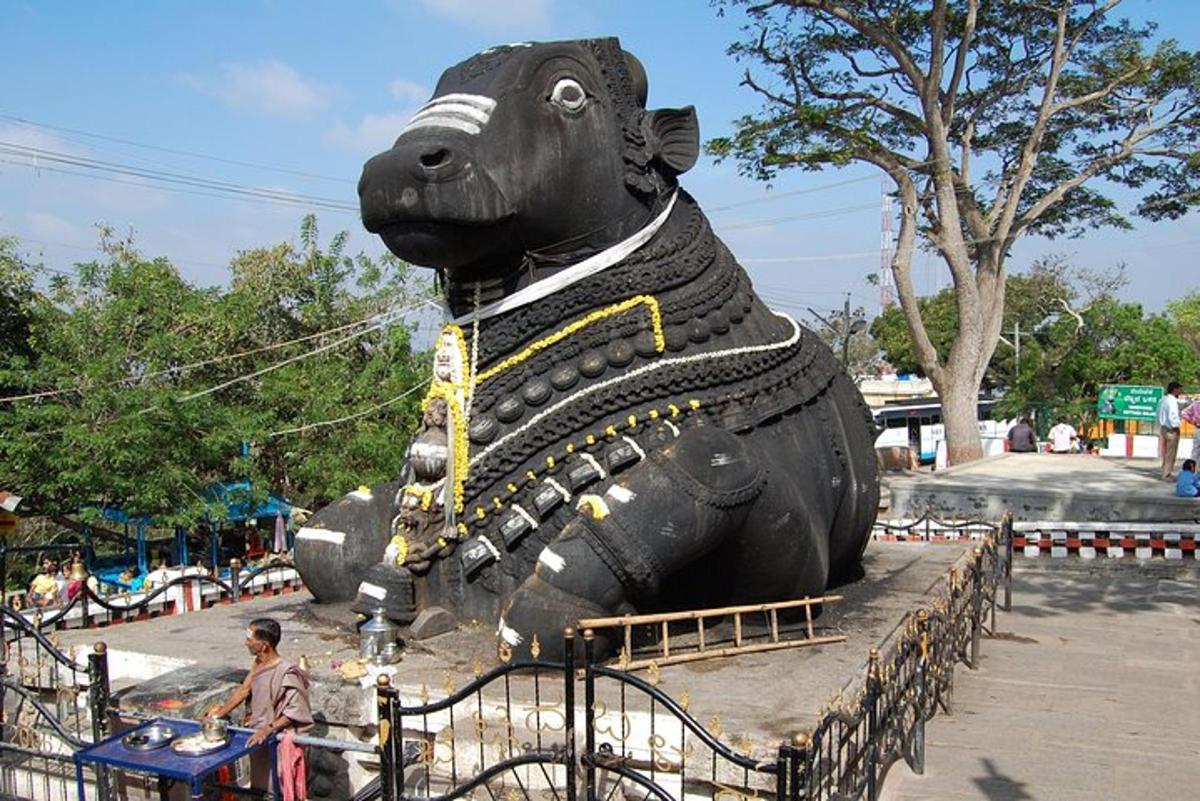 a person sitting next to a large bear statue