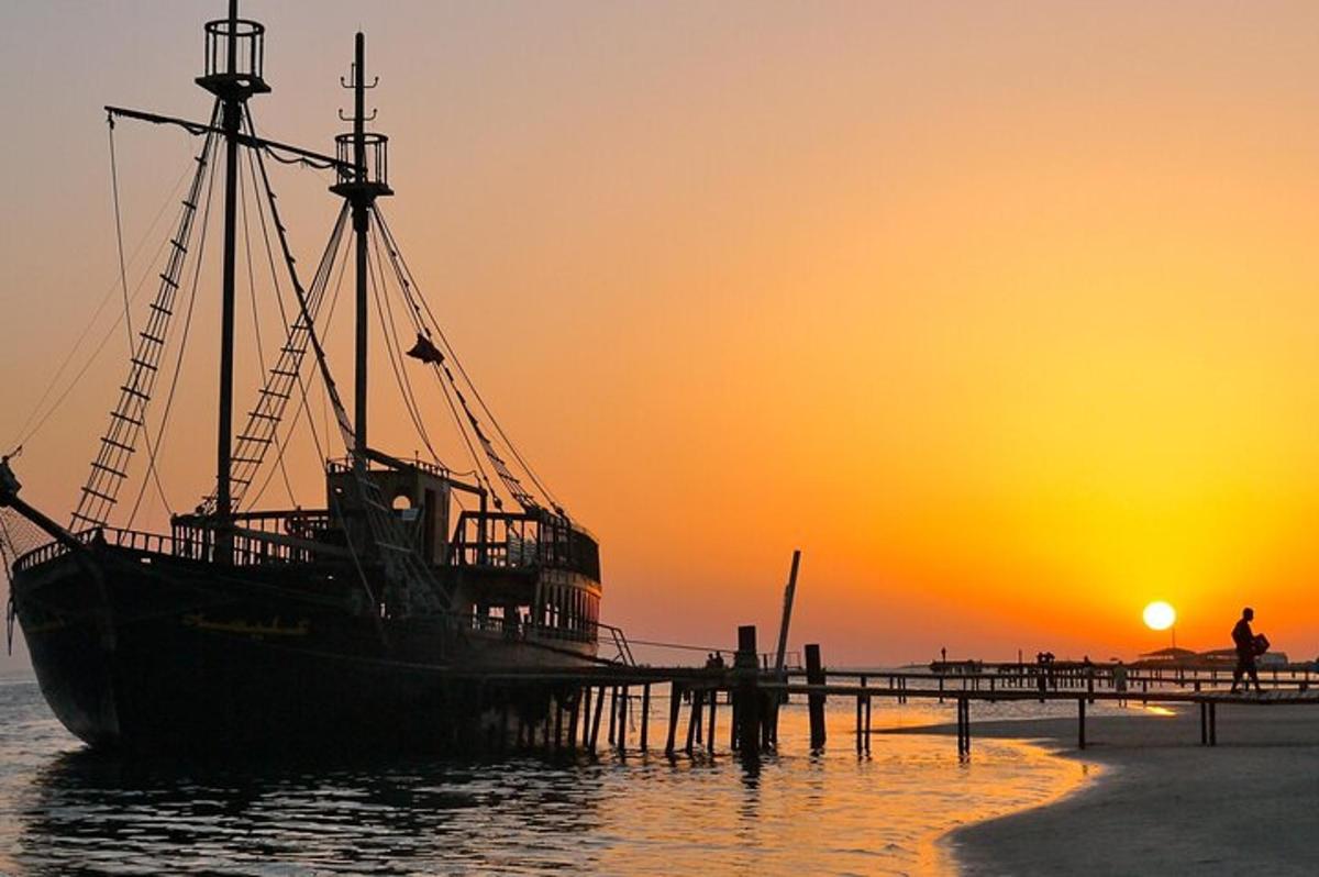 a boat sitting next to a dock with the sunset