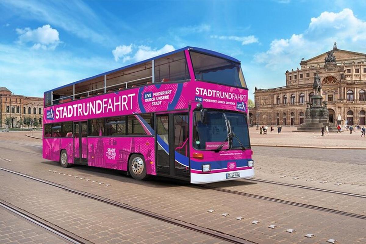 a pink double decker bus in front of a building
