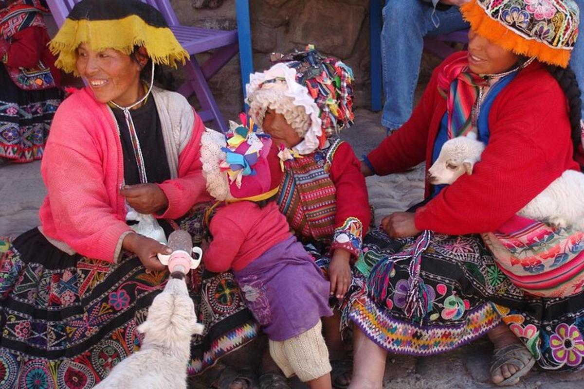 un gruppo di donne sedute a terra con una capra