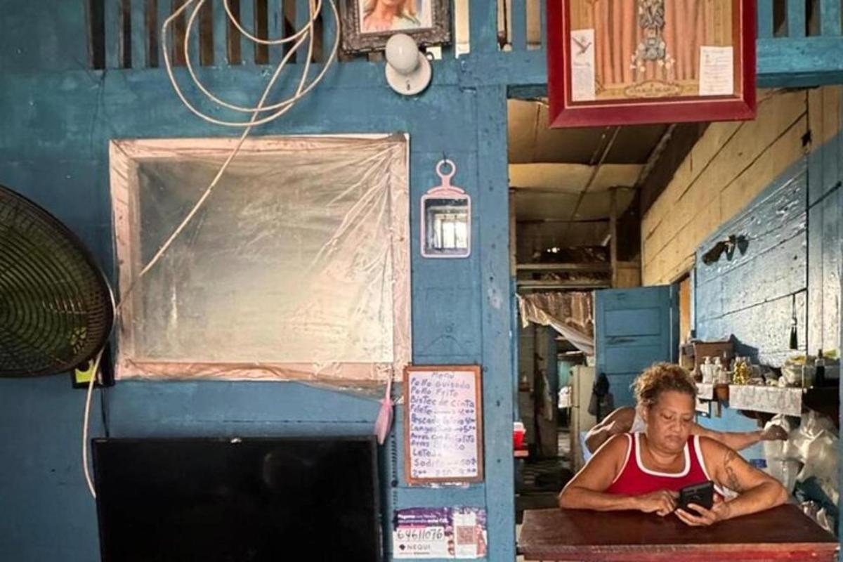 una dona asseguda a una taula mirant un telèfon mòbil