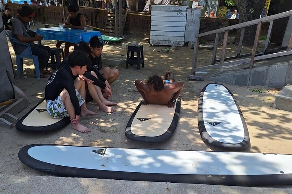 un gruppo di persone sedute su tavole da surf a terra