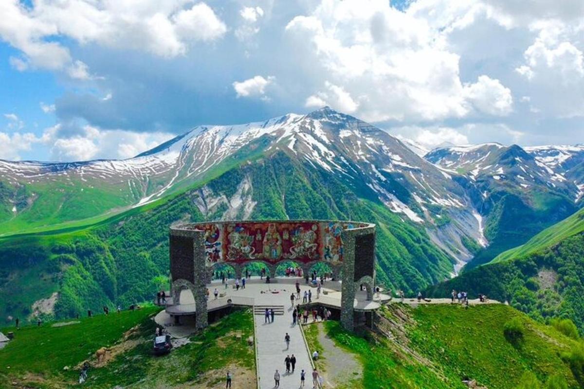 un grand bâtiment sur une colline avec des montagnes en arrière-plan