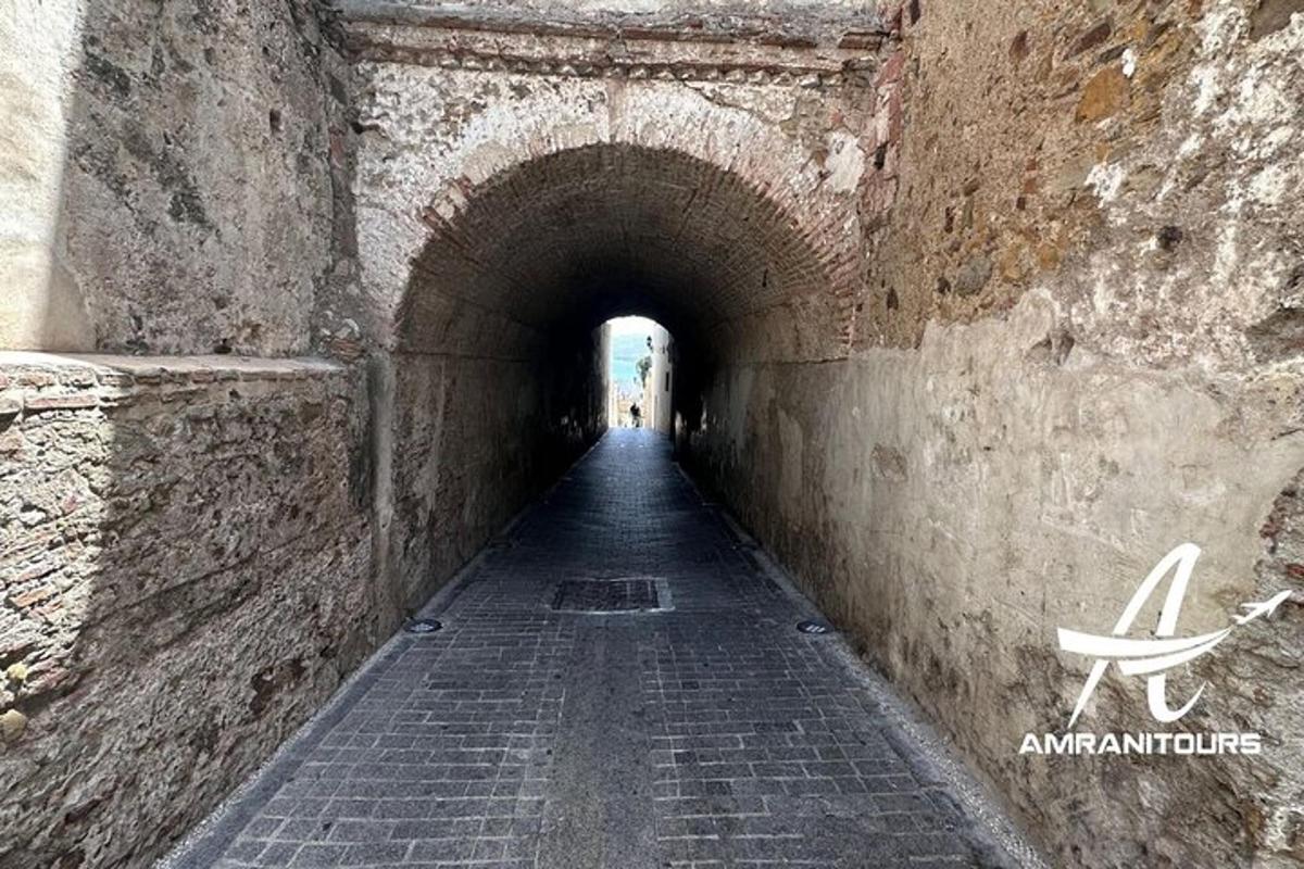 a tunnel in a stone wall with a person walking through it