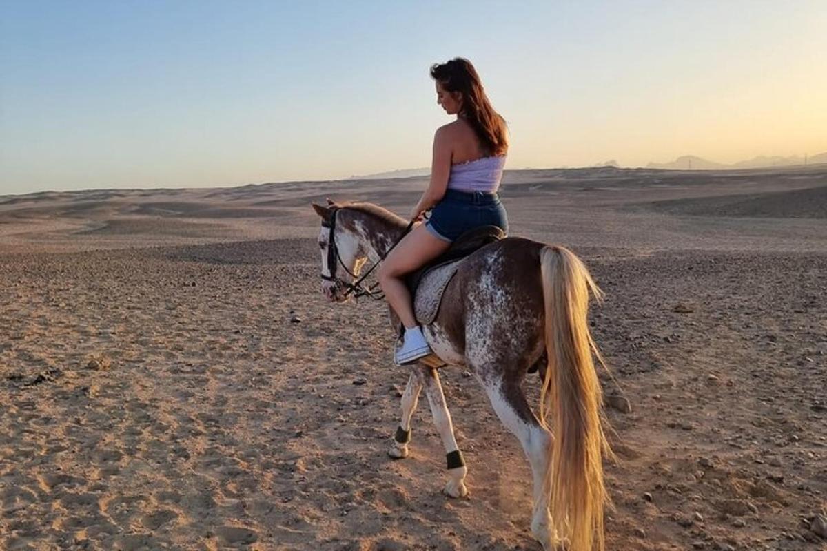 uma mulher cavalgando um cavalo no deserto