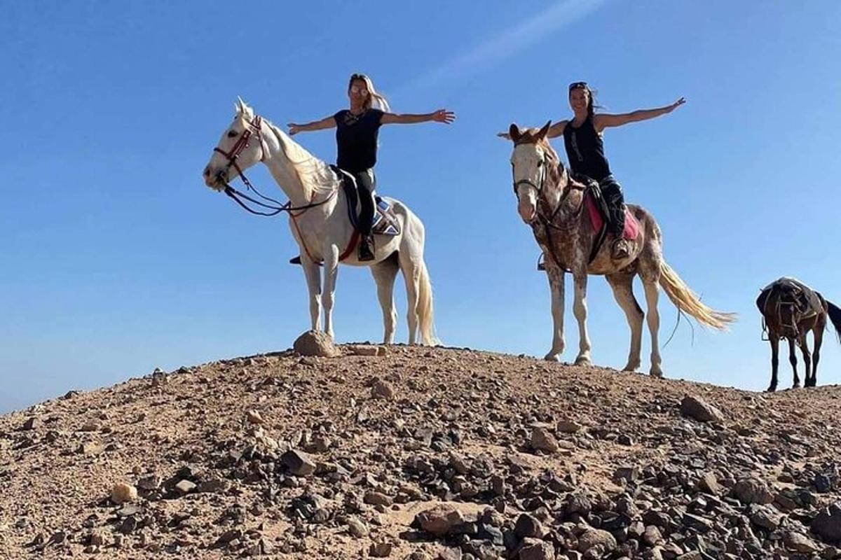duas mulheres cavalgando no topo de uma colina
