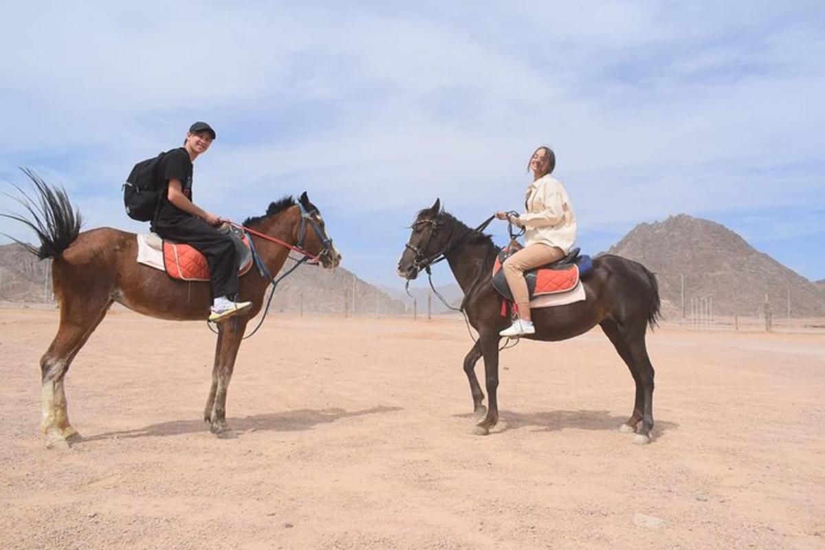 dues persones muntant a cavall al desert