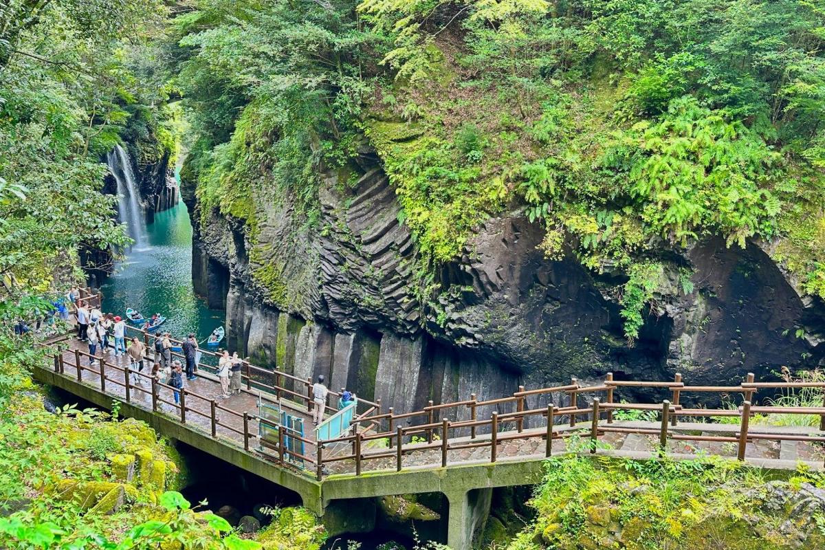people standing on a bridge over a river with a waterfall