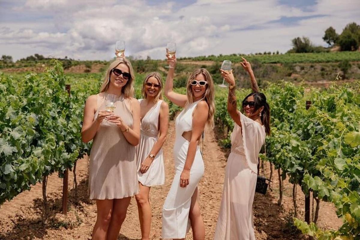 un gruppo di donne in piedi in un vigneto con in mano bicchieri di champagne