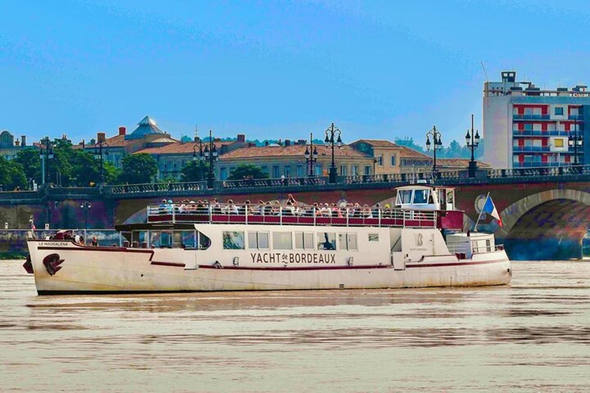 a white boat on the water near a bridge