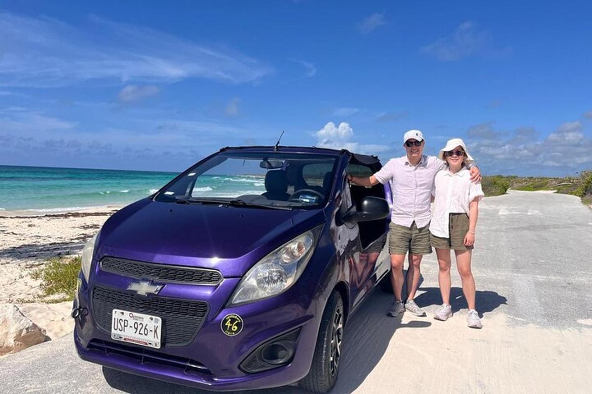un uomo e una donna in piedi accanto a un'auto viola sulla spiaggia