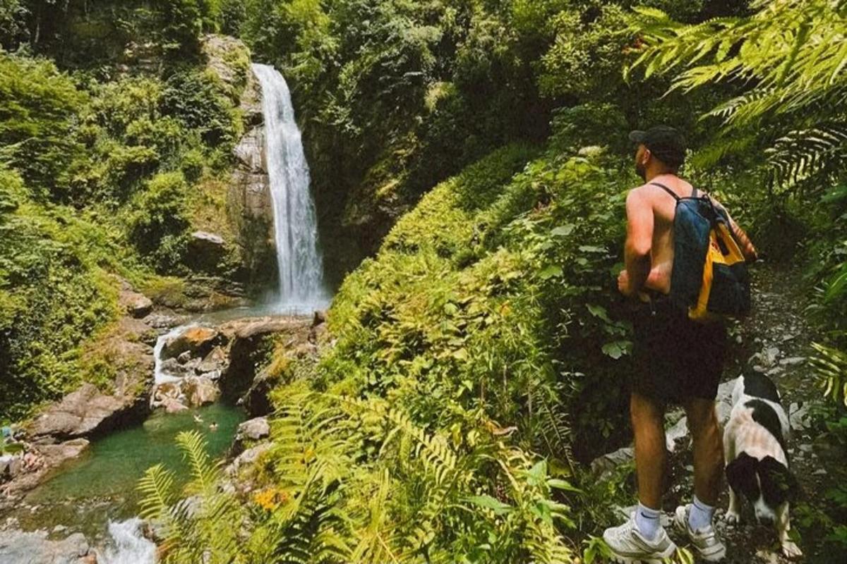 seorang lelaki berdiri di hadapan air terjun