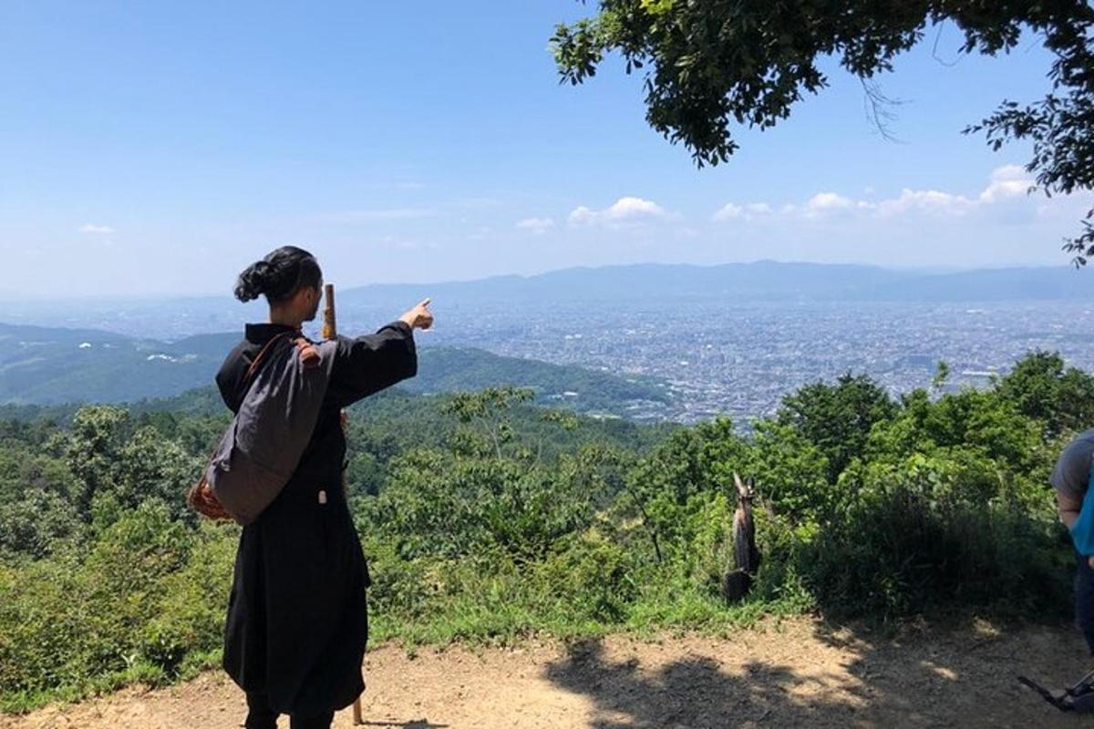 seorang wanita berdiri di atas bukit menunjuk ke arah bandar