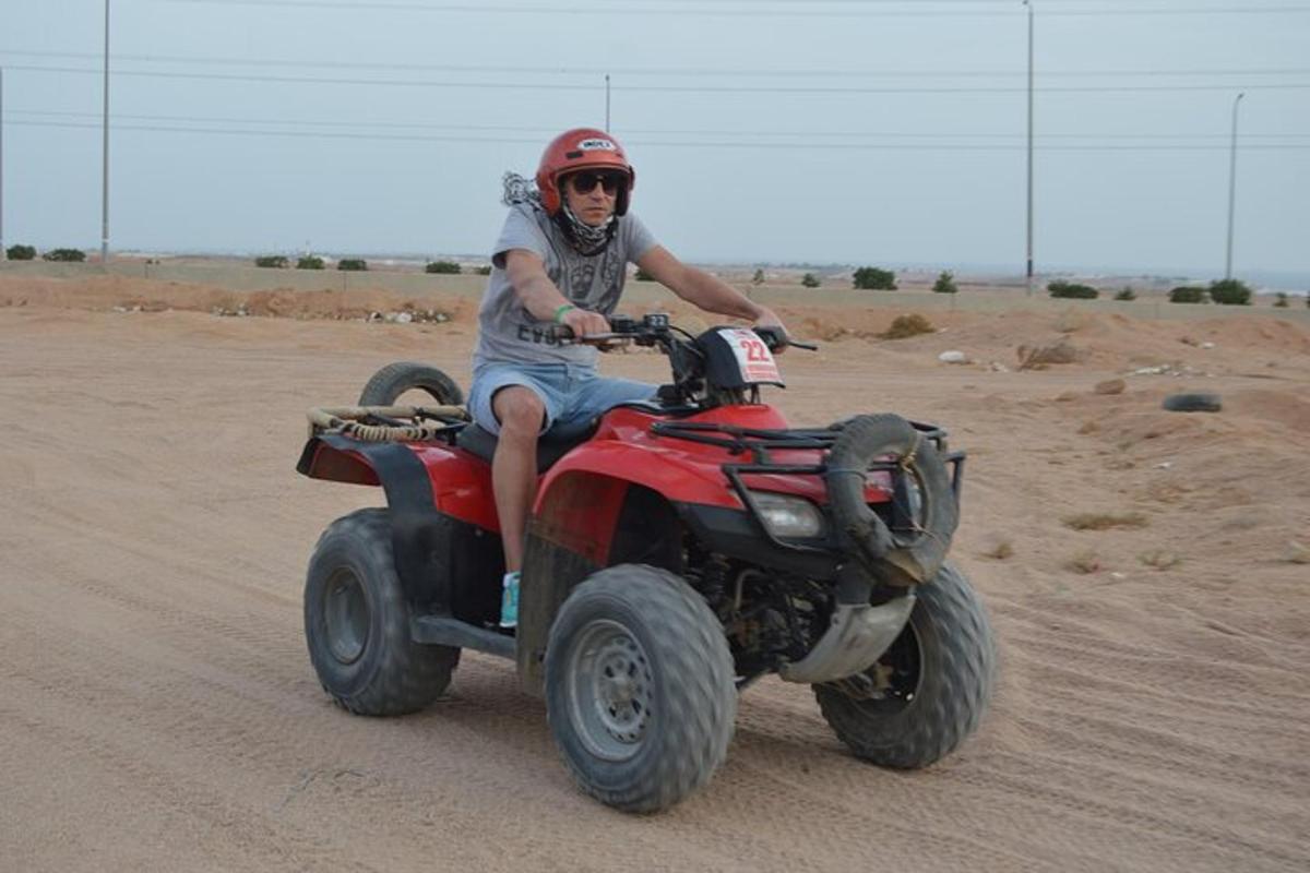 ein Mann, der mit einem Quad durch die Wüste fährt