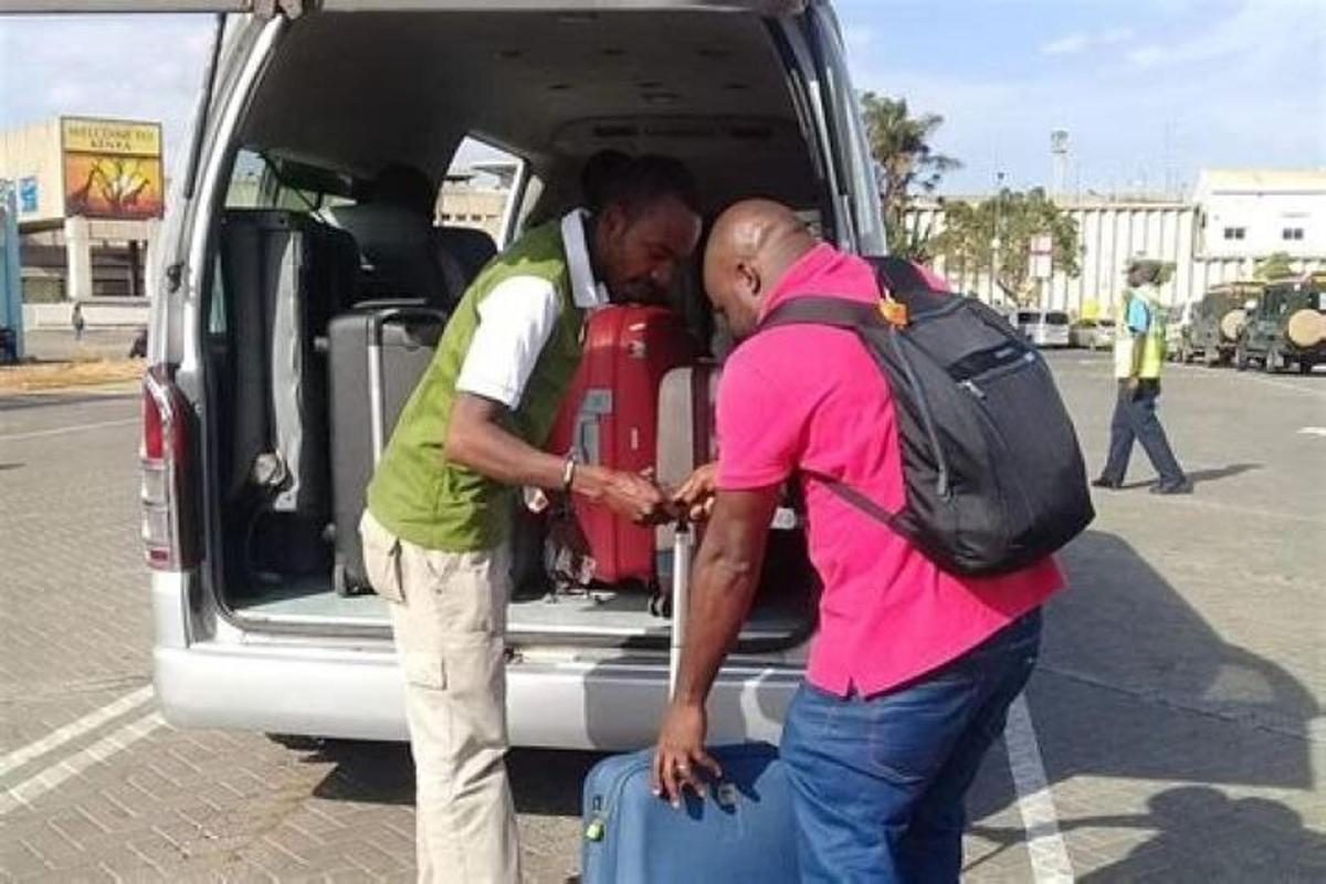 two men loading luggage into the back of a van