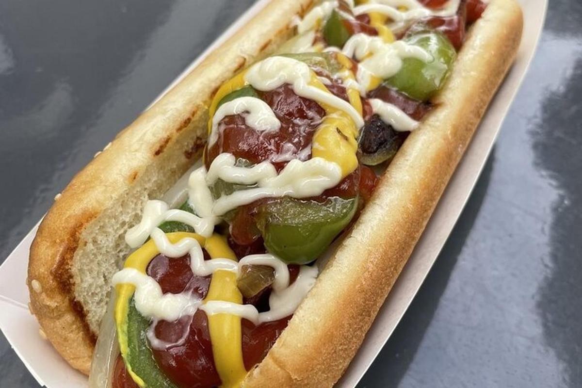 a hot dog with toppings in a paper container