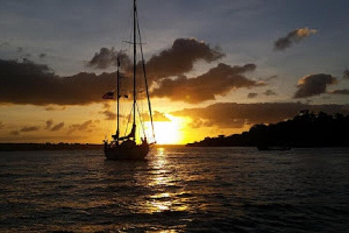 a sail boat in the water at sunset