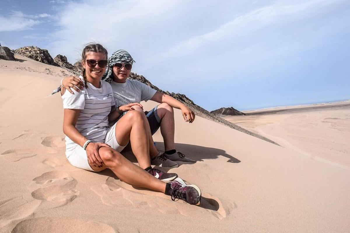un uomo e una donna seduti sulla sabbia della spiaggia