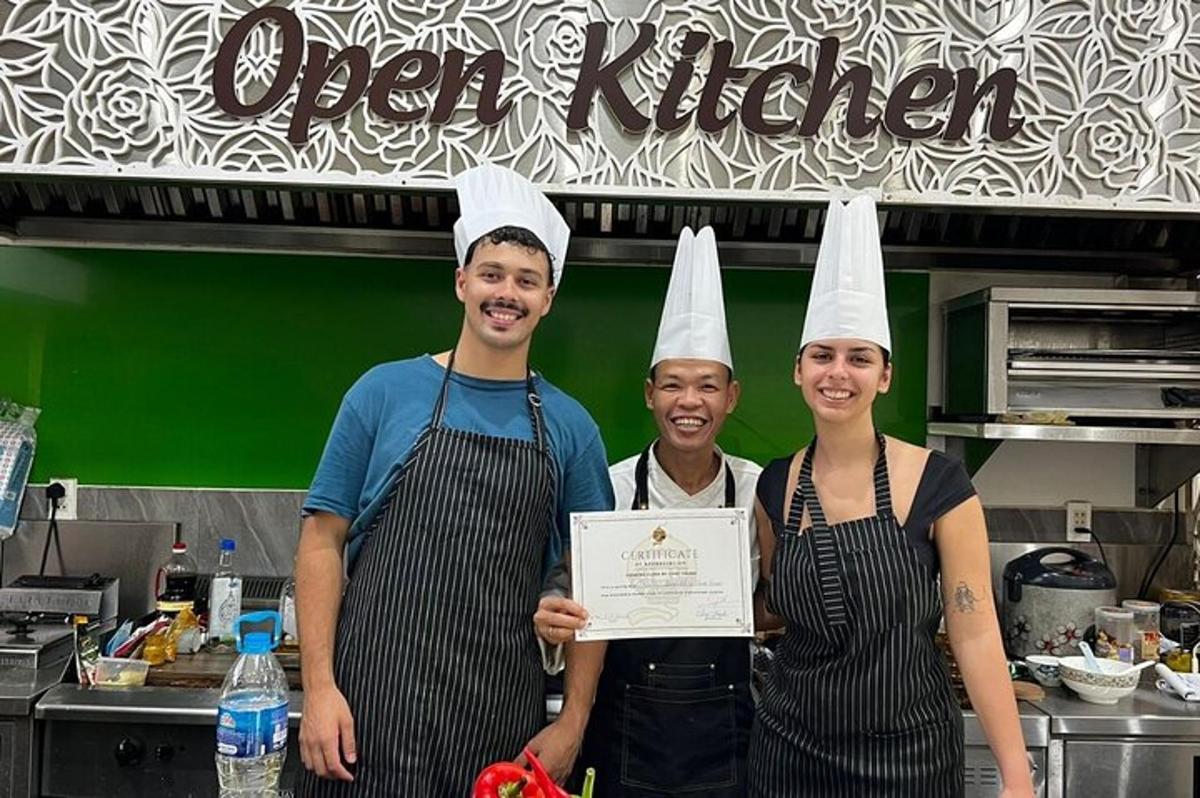 tre persone con cappelli da chef che tengono un cartello in una cucina