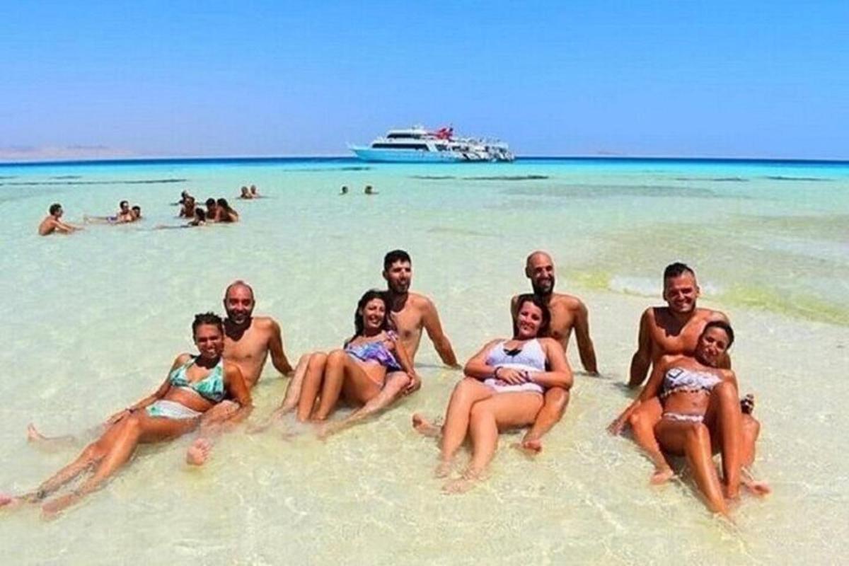 eine Gruppe von Menschen, die im Sand an einem Strand sitzen