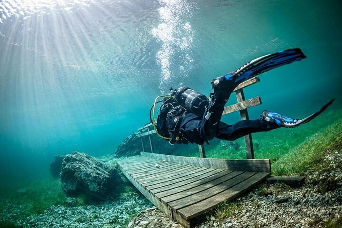 Un buceador en el agua junto a una plataforma de madera en el agua.