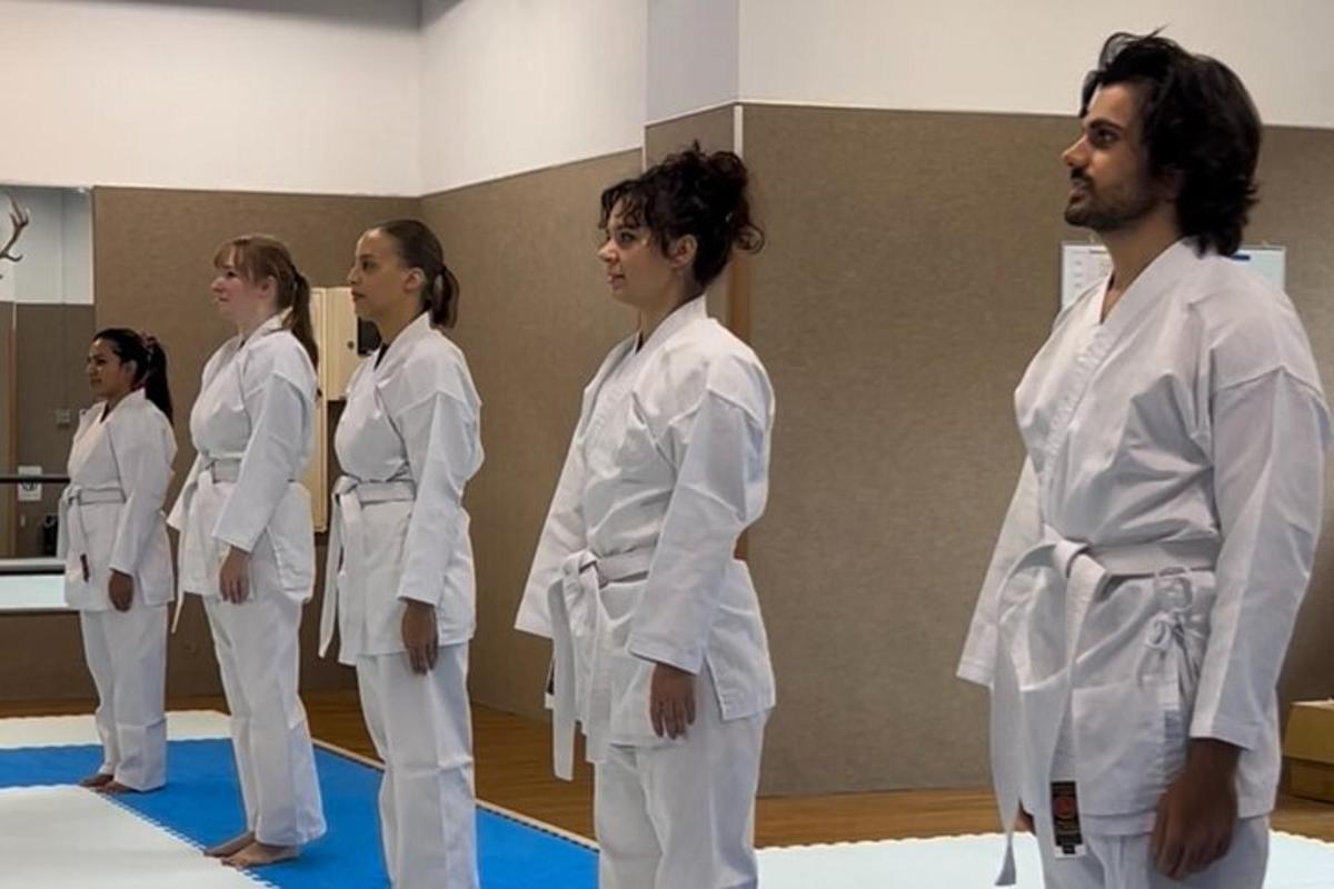 Skupina lidí v bílých judistických uniformách v tělocvičně