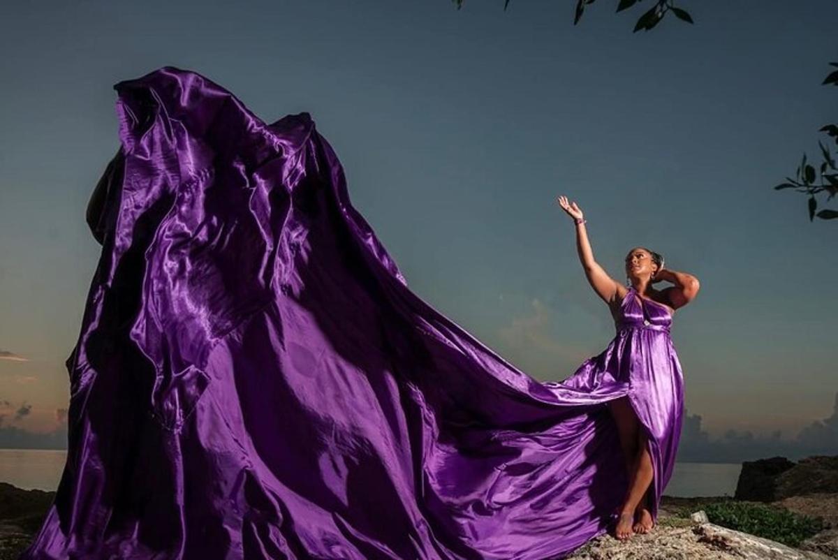 a woman in a purple dress is waving