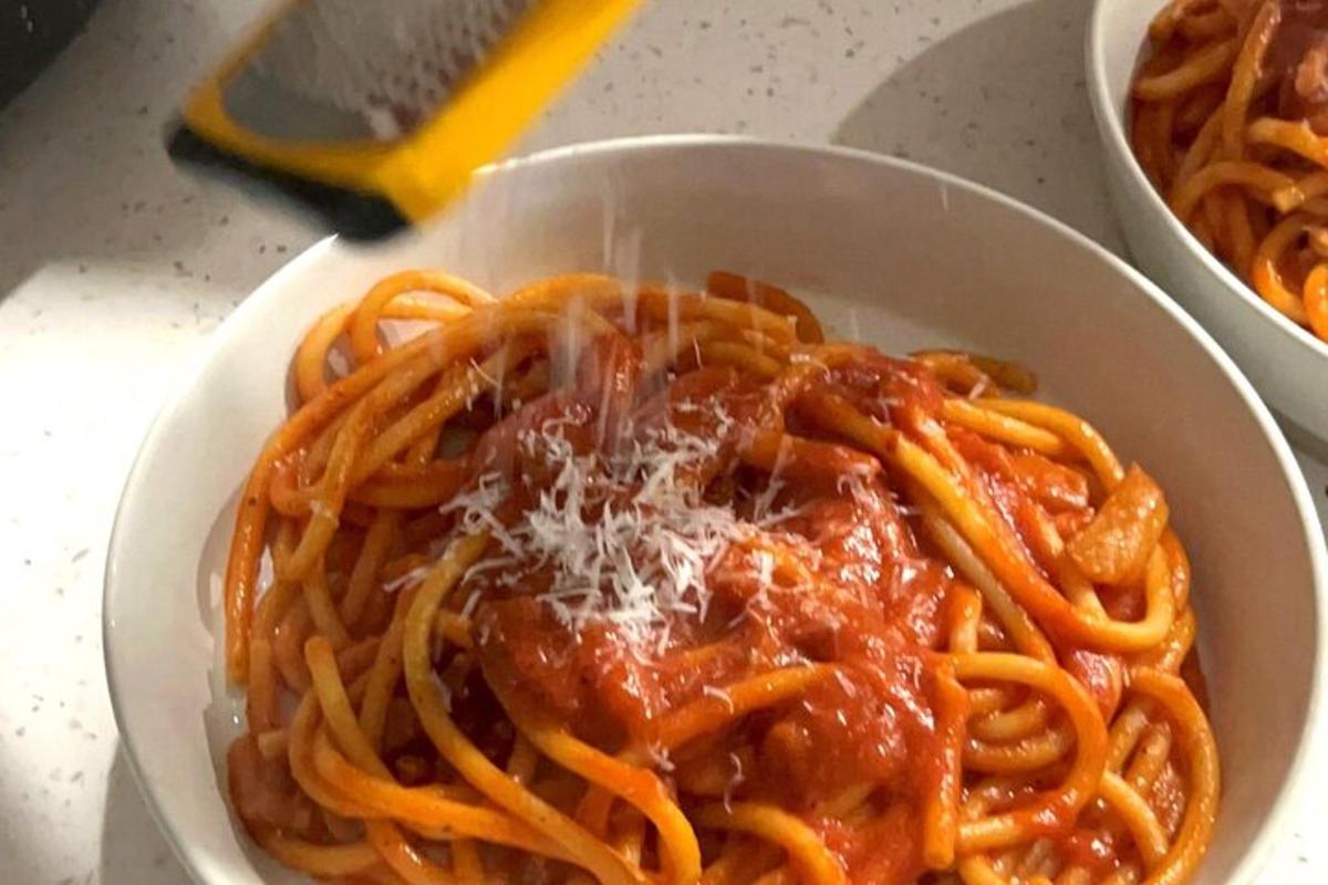 isang mangkok ng spaghetti na may sarsa at keso sa mesa