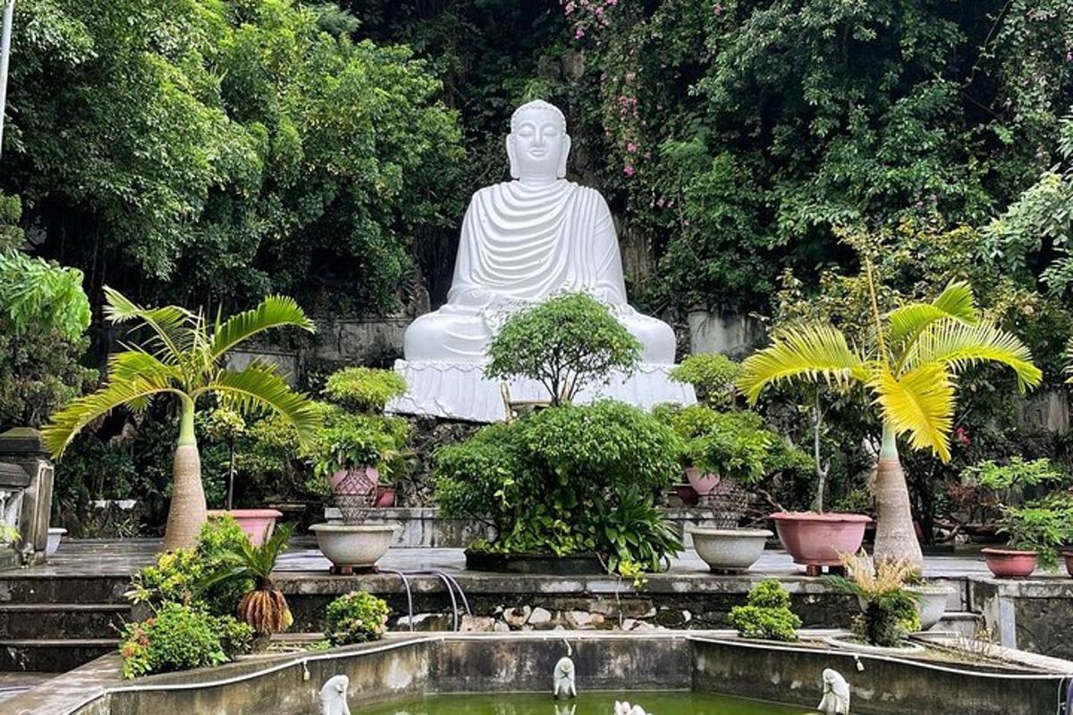 una grande statua bianca in un giardino con uno stagno