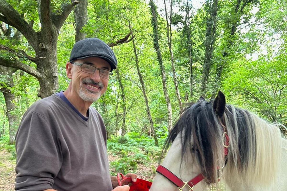 a man standing next to a horse in the woods