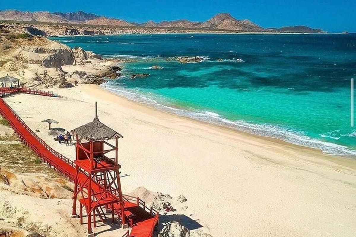 uma torre de salva-vidas vermelha em uma praia com o oceano