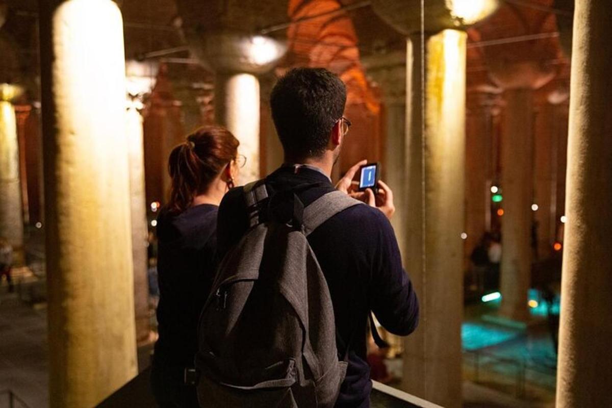 Un hombre con una mochila tomando una foto con su teléfono celular.
