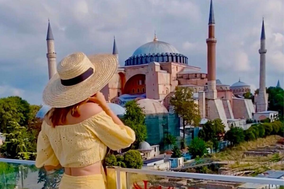 Una mujer con sombrero mirando una mezquita