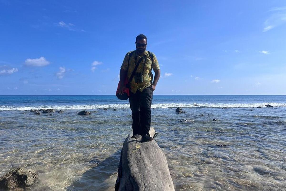 a man standing on top of a log in the ocean