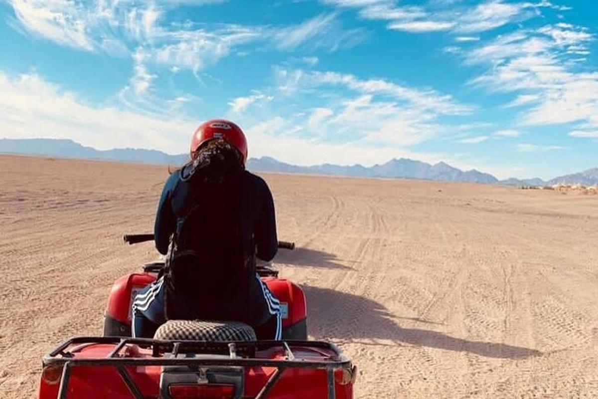 seseorang yang menunggang basikal quad di padang pasir