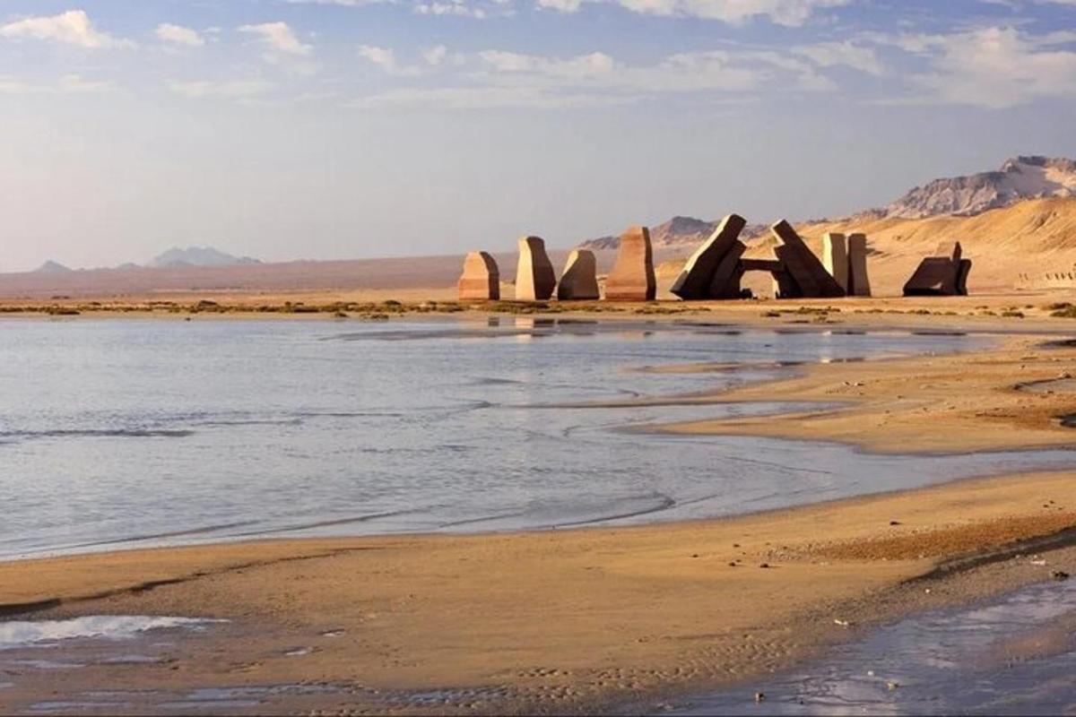 egy csoport Stonehenge áll a homokban a tengerparton