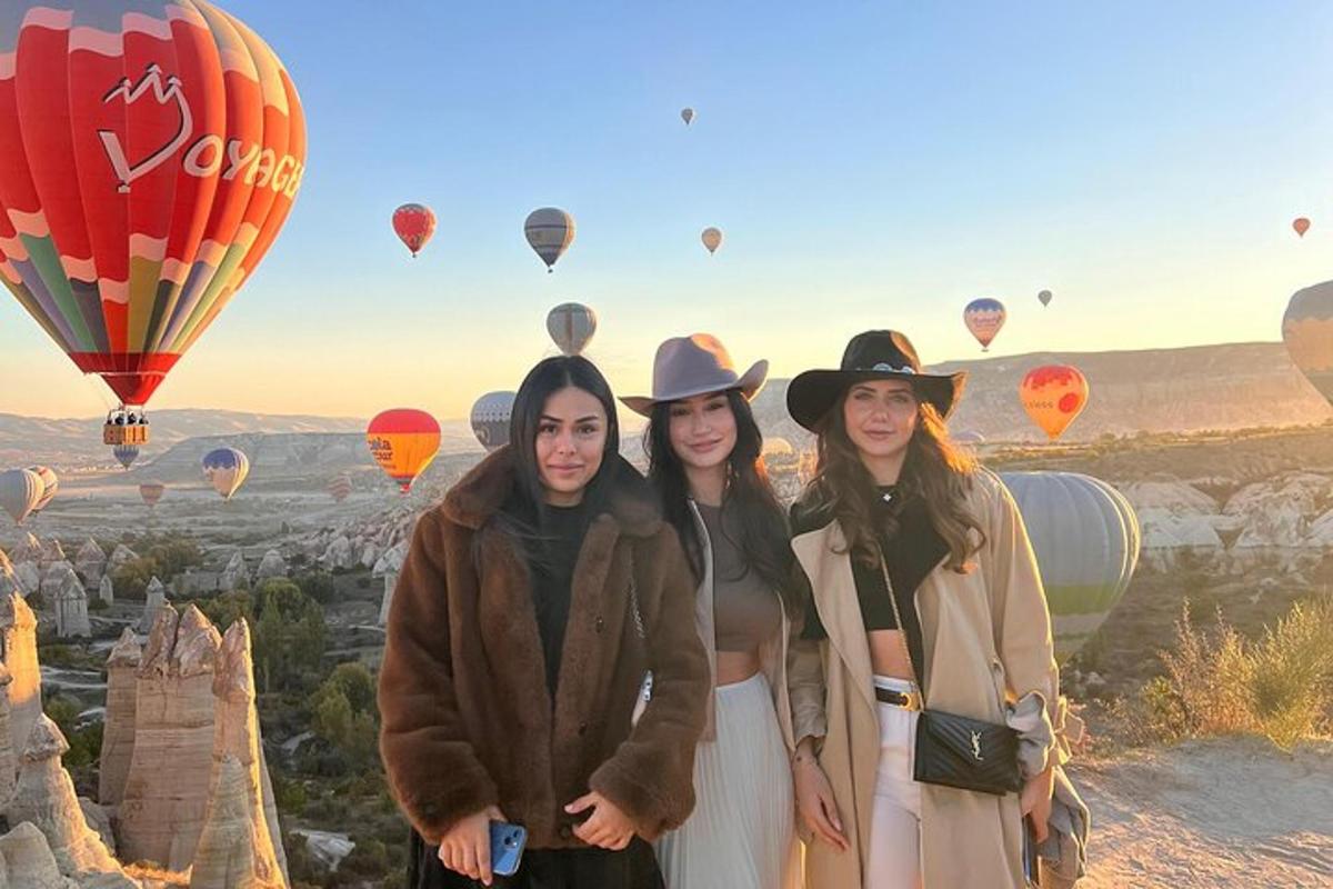 three women standing in front of a view of hot air balloons