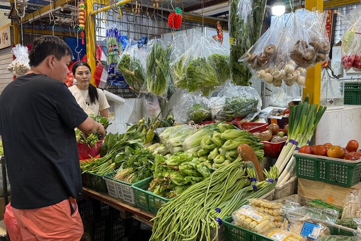 một người đàn ông đứng trong chợ với một đống rau