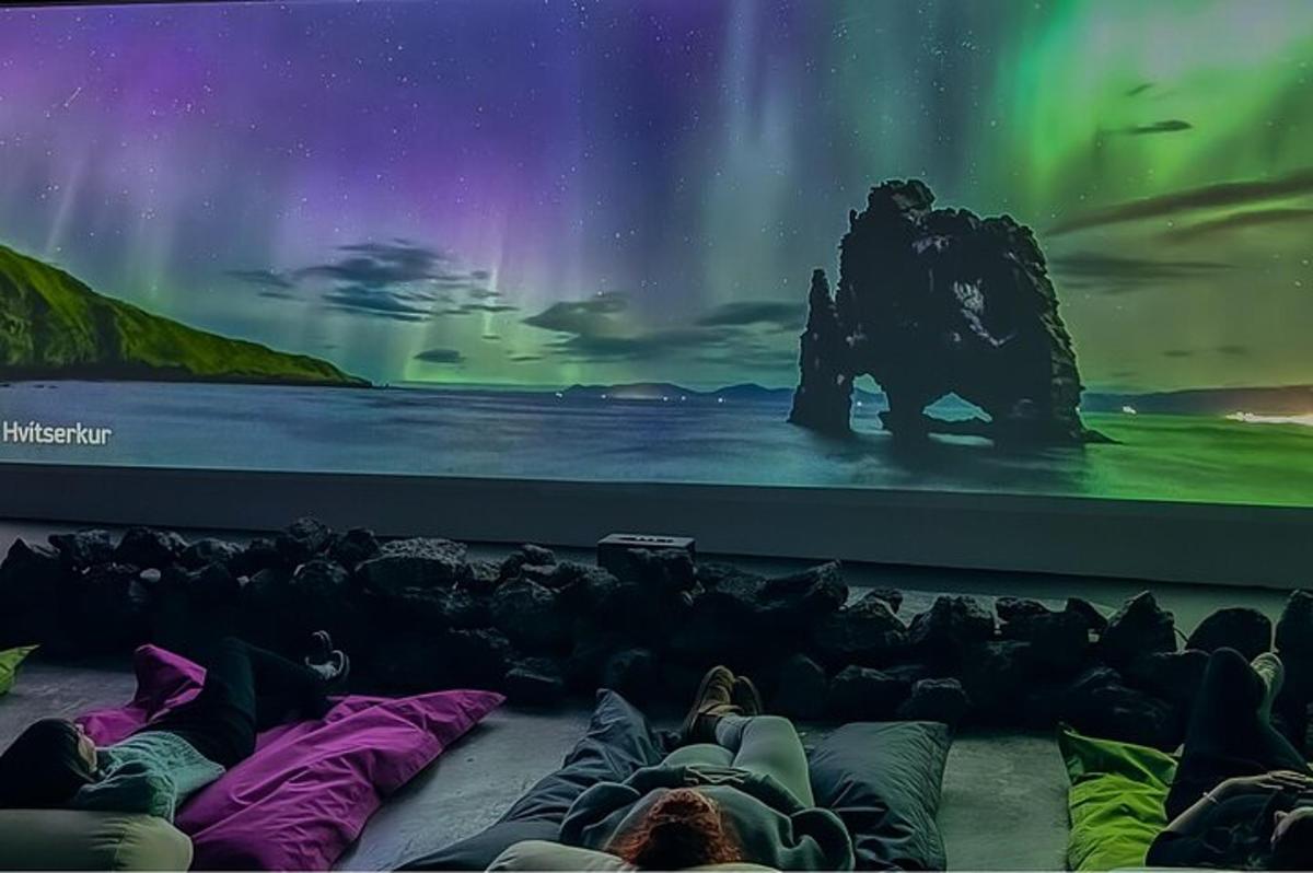 a group of people laying on pillows in front of a large screen