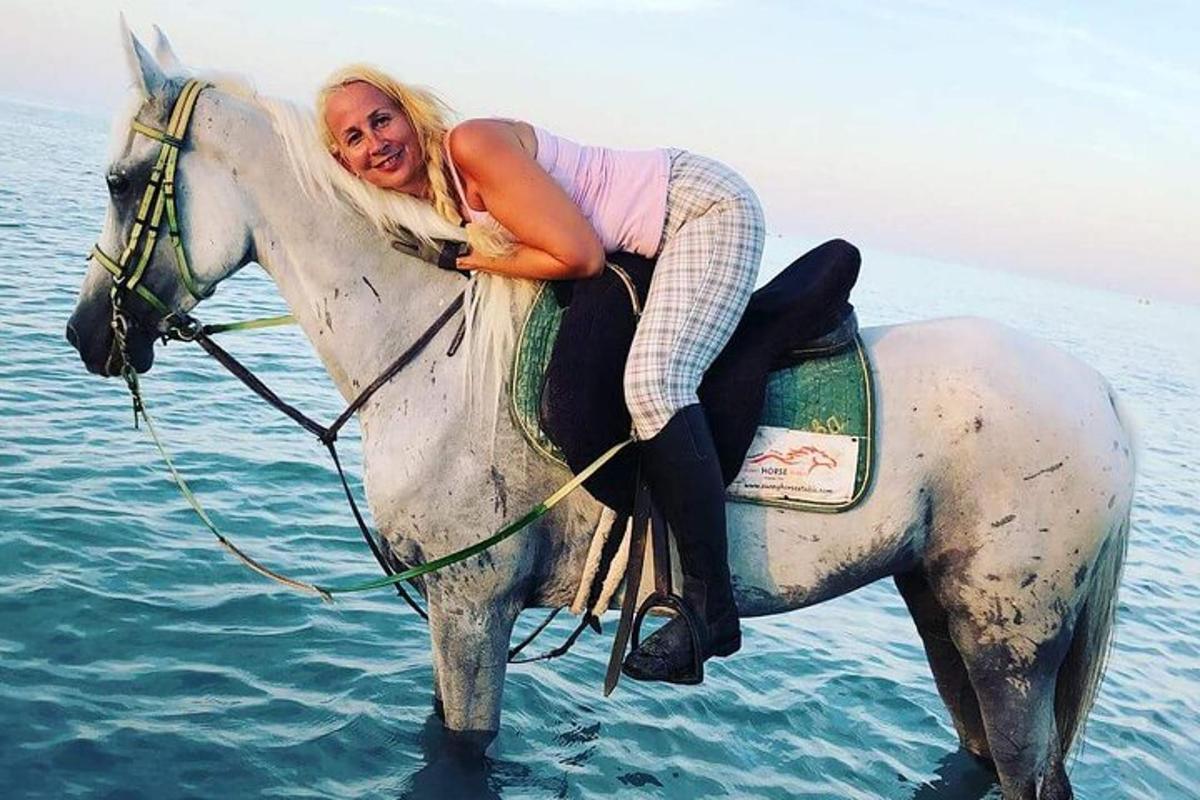 una donna che cavalca un cavallo bianco nell'acqua