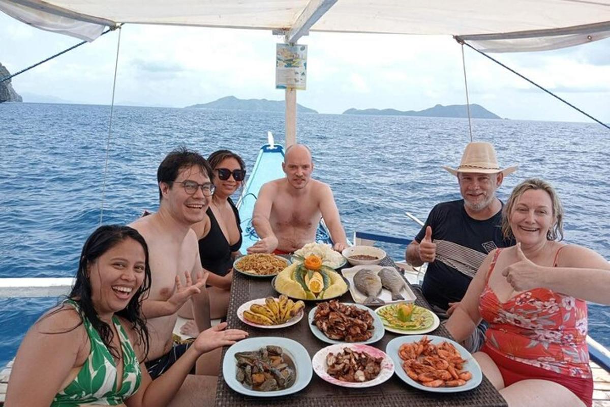 a group of people sitting around a table with food on a boat