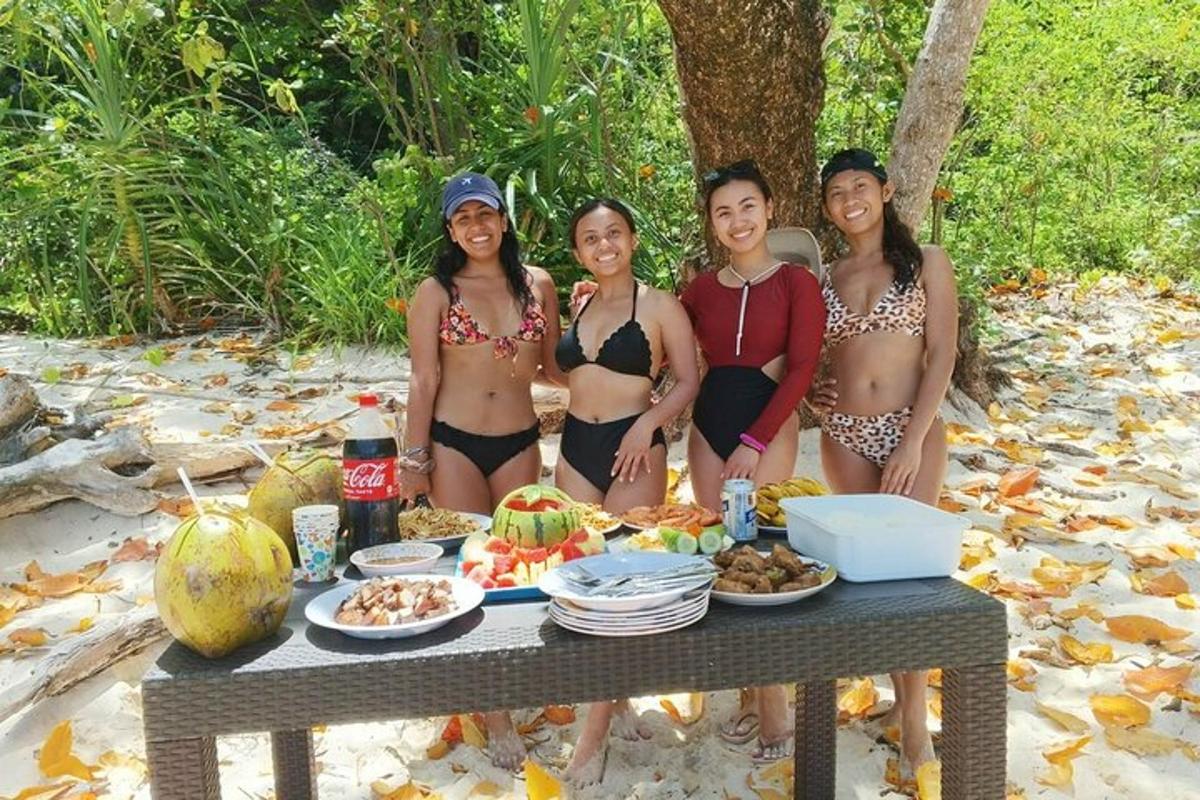 four women in bikinis standing next to a table with food