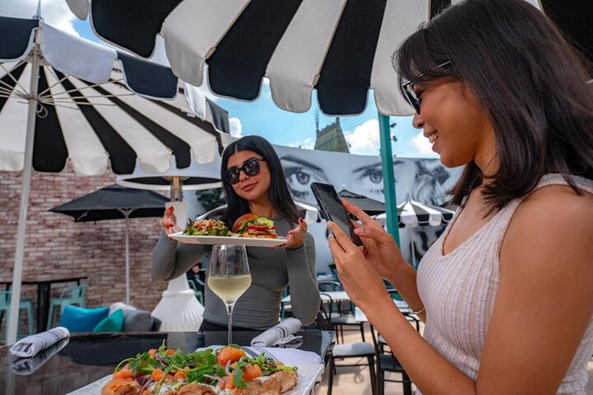eine Frau hält einen Teller mit Essen und schaut dabei auf ihr Handy