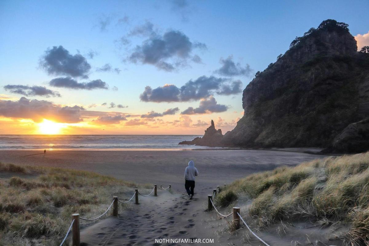 un hombre caminando por una playa de arena al atardecer