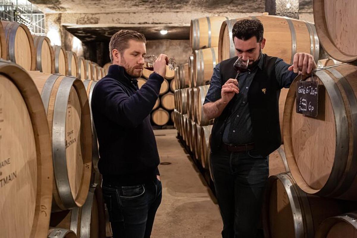 two men standing in a wine cellar with barrels