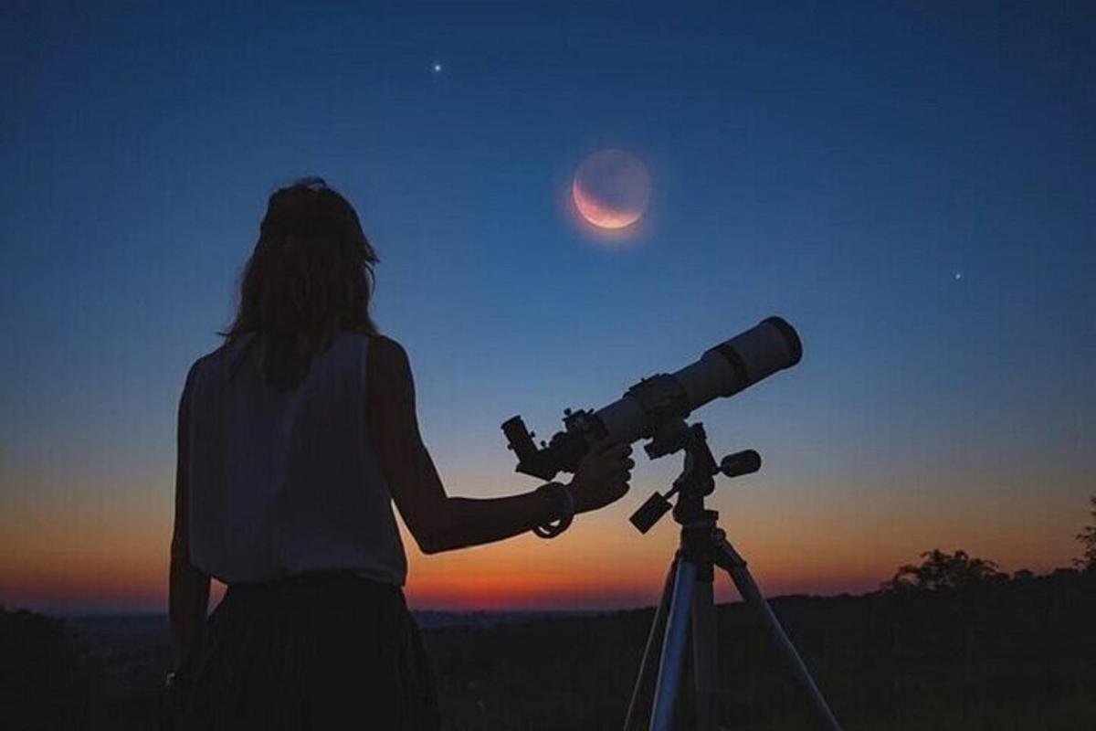 a woman looking at the moon through a telescope